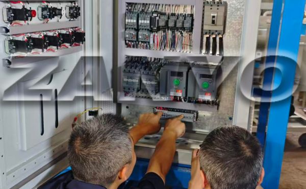 Technicians inspecting an oil purifier control cabinet.
